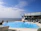 Image of a couple relaxing by the villa’s infinity pool overlooking the ocean at sunset.
