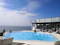 Image of a couple relaxing by the villa’s infinity pool overlooking the ocean at sunset.