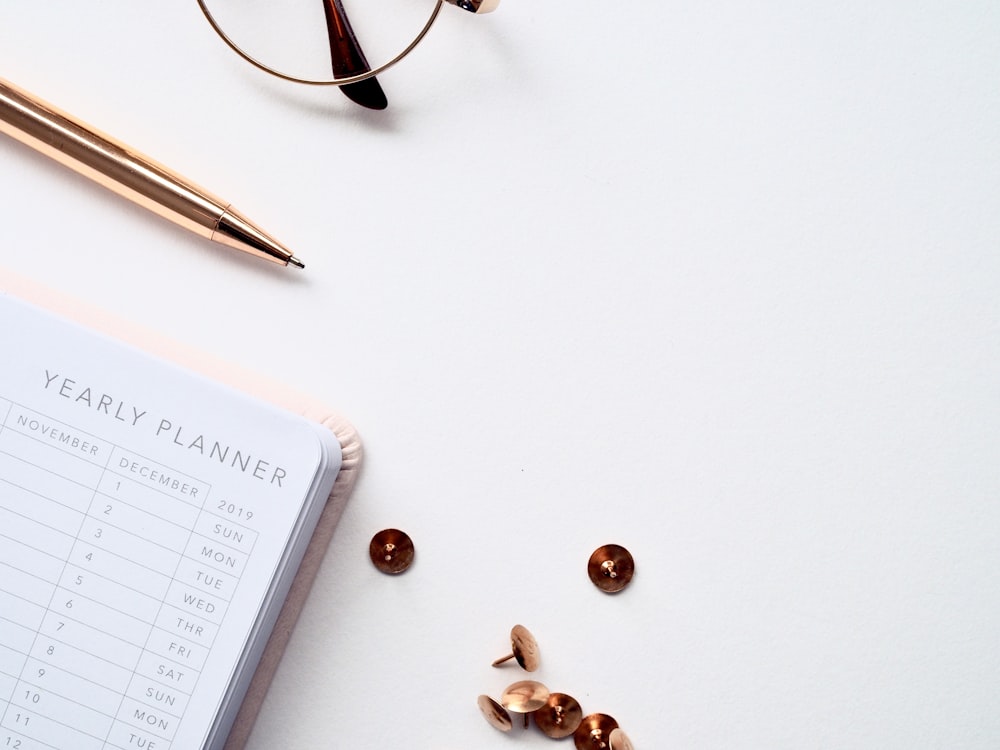 buttons and thumbtacks beside planner book on table