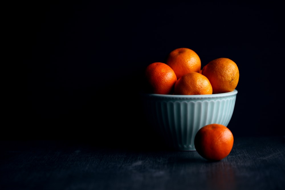 frutta arancione in ciotola di ceramica bianca