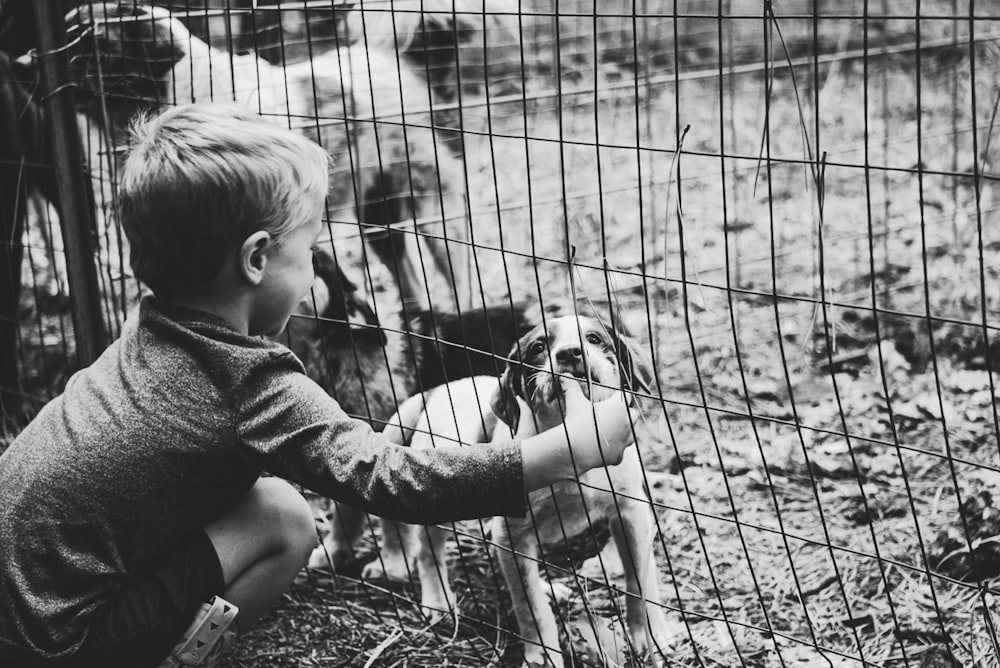 grayscale photography of boy holding dog