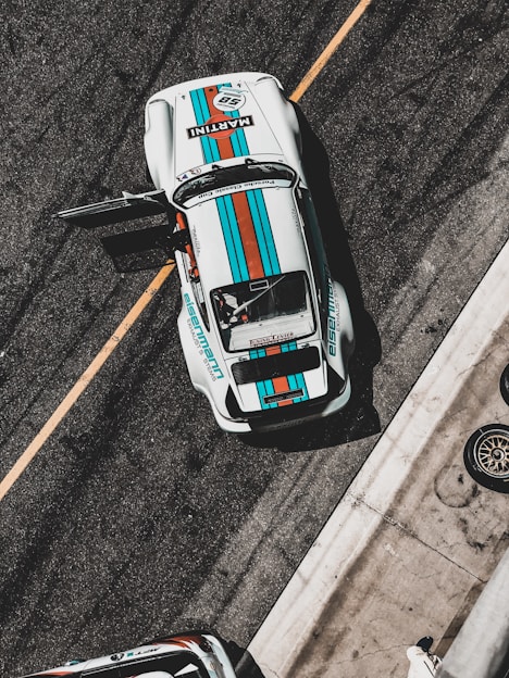 white, teal, and red sports car on park with door open during daytime