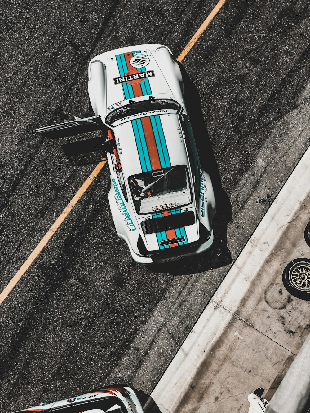 white, teal, and red sports car on park with door open during daytime