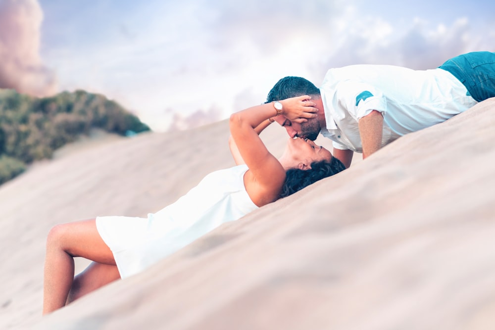 couple kissing while lying on desert