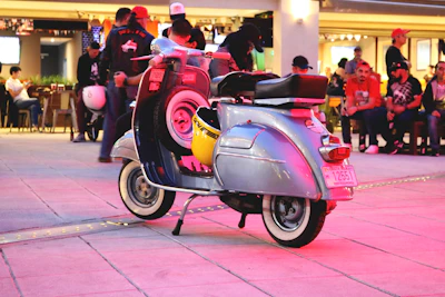 A warm gathering of Lambretta club members enjoying a sunny outdoor meetup with scooters parked nearby.