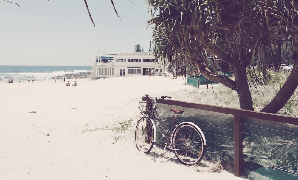 bicycle parked beside wooden railing near beach