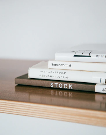 An elegant stack of Laide Fujah’s books resting on a minimalist wooden desk.