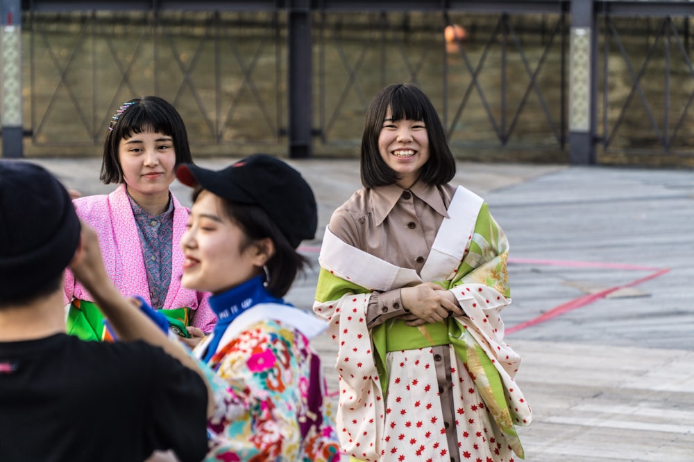 Cuatro mujeres sonrientes de pie en el pavimento durante el día