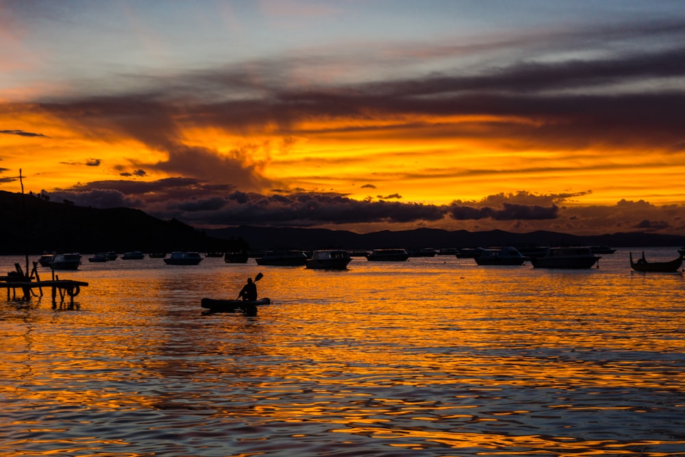 silhouette di persona che cavalca in barca durante l'ora d'oro