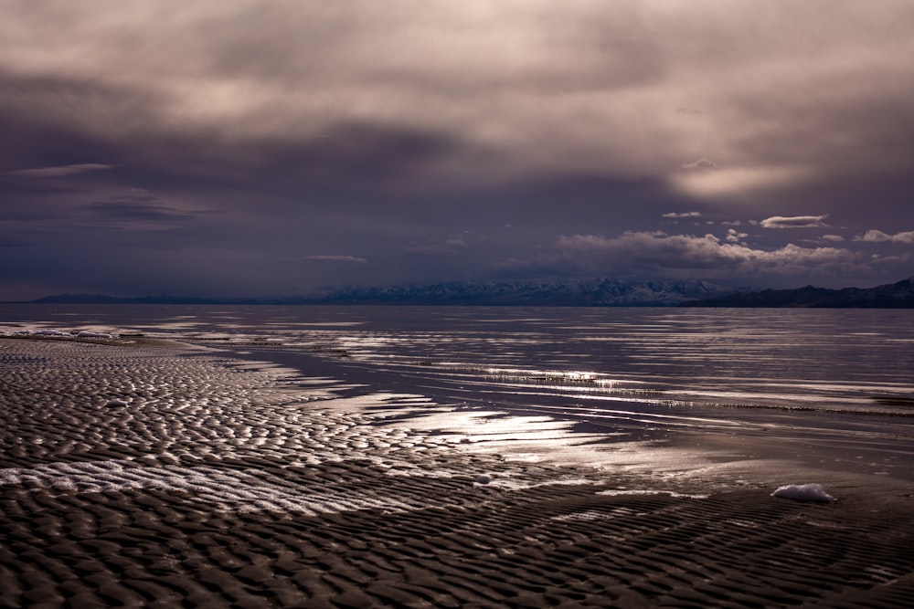 body of water under cloudy sky during sunset