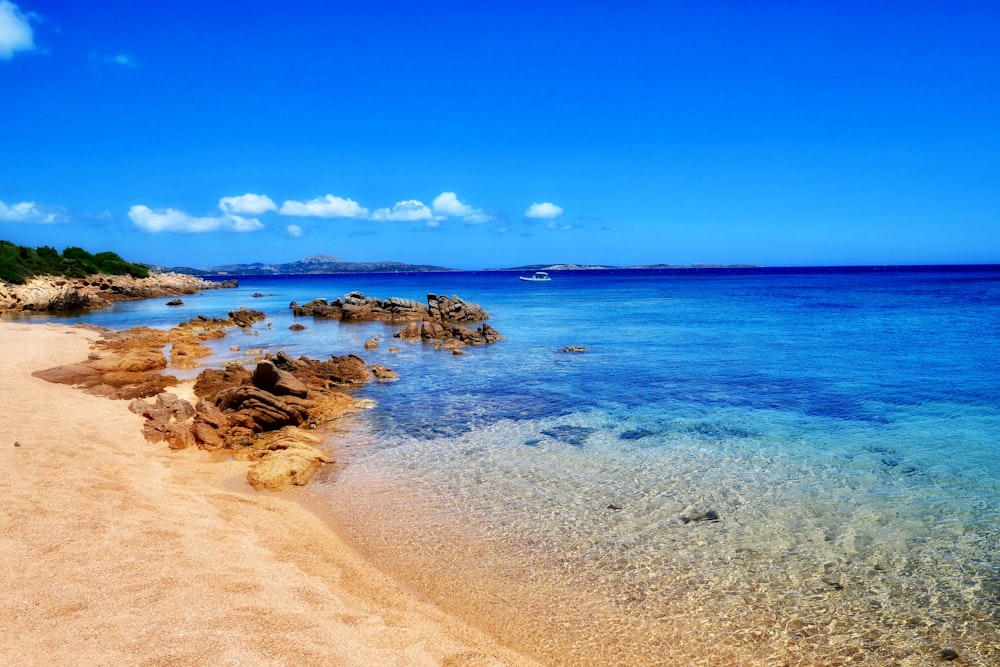 rocks on seashore under clear blue sky at daytime