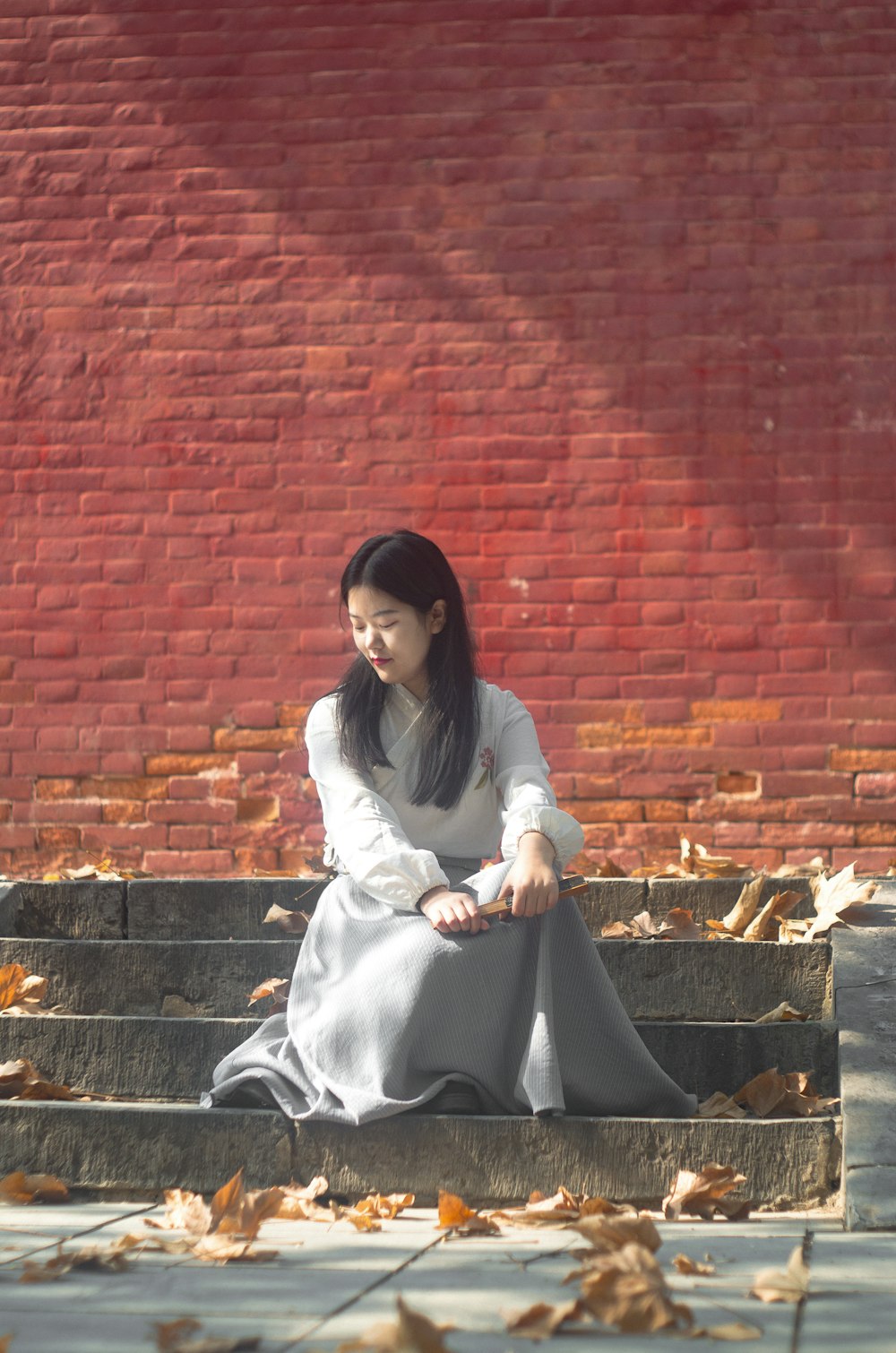 昼間、葉っぱの近くの灰色の階段に座っている女性