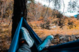 A hiker relaxing in a golite hammock overlooking a vast valley with colorful autumn leaves.