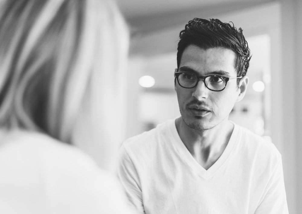 grayscale photography of man wearing eyeglasses in front of woman
