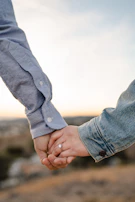 Gilson and Daniely holding hands during a serene outdoor prayer moment, with gentle blue skies behind them.
