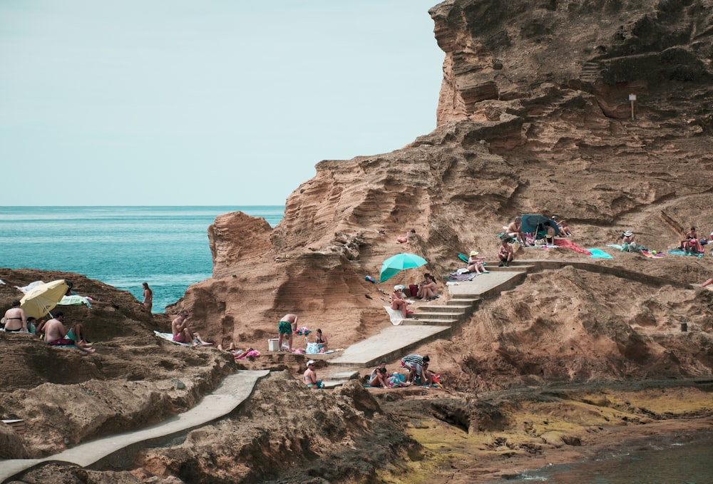 people on rock formation near body of water