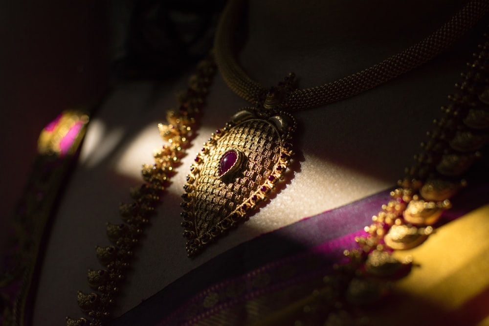 gold-colored necklace with red gemstone