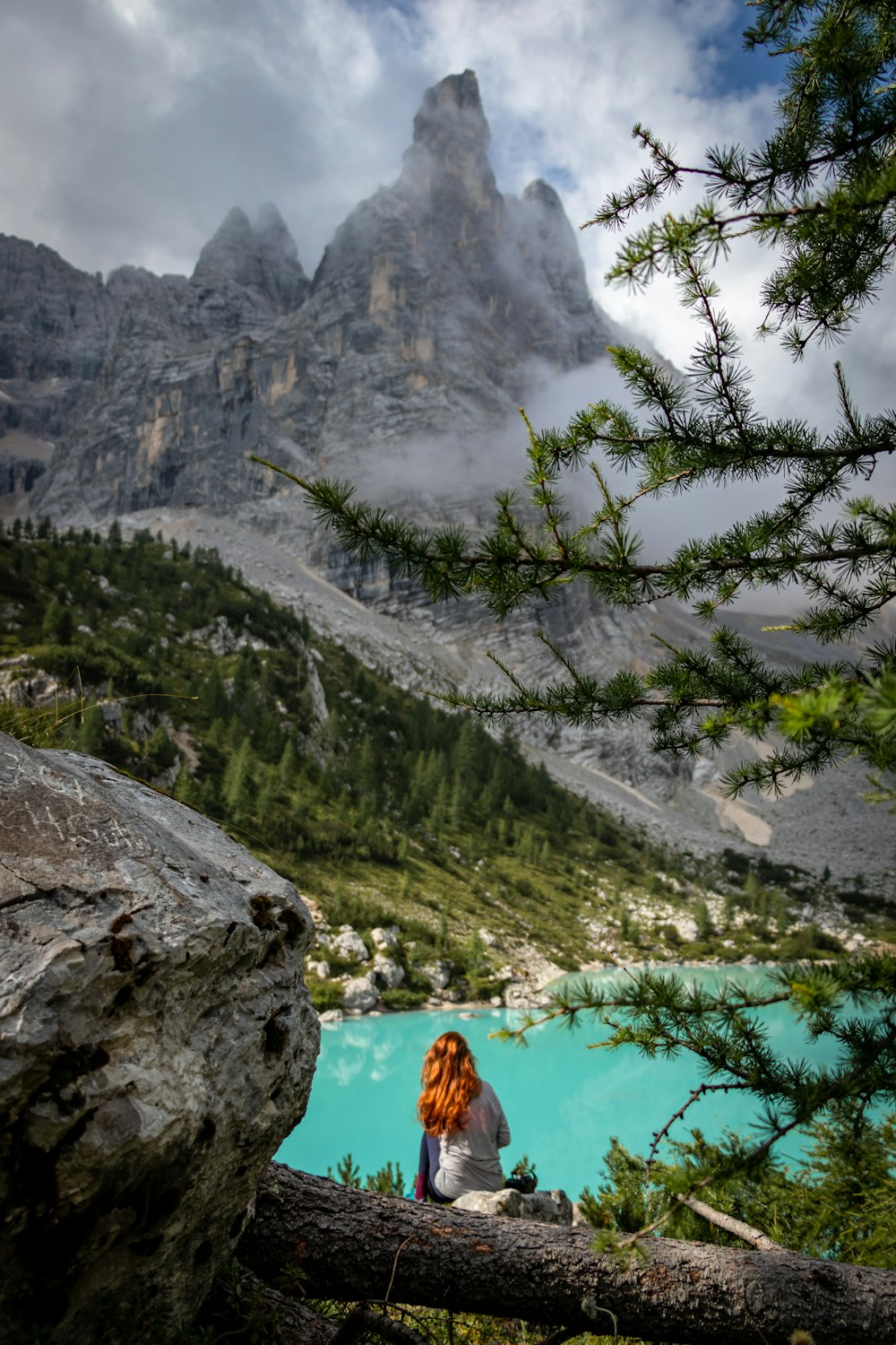 woman sitting in front of body of water during daytime