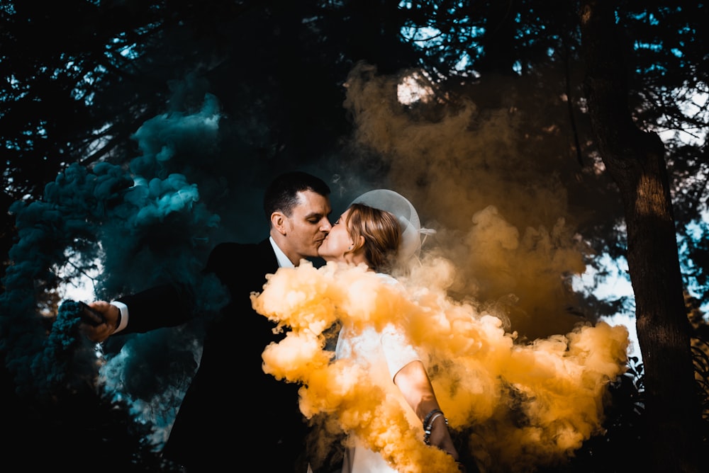 man and woman kissing with yellow smoke