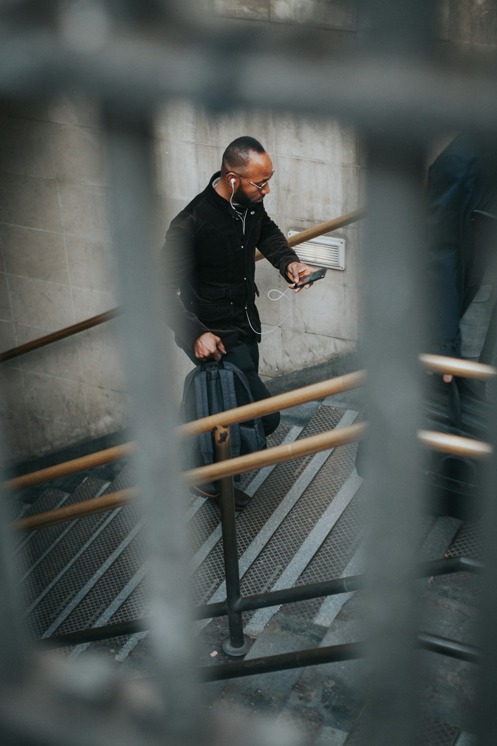man on stairs while using smartphone and carrying backpack