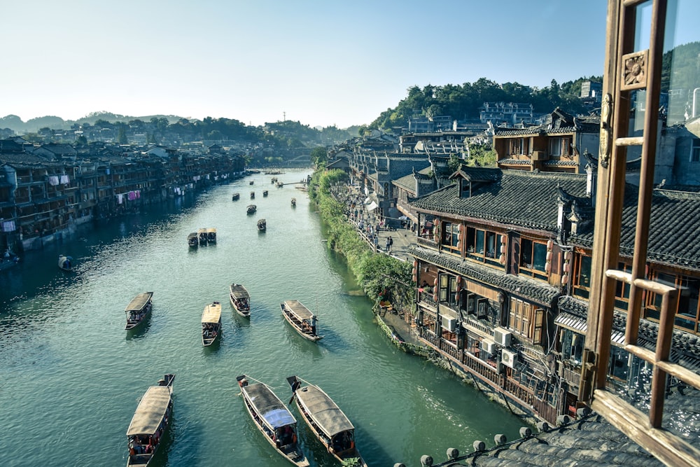 bird's eye view photography of boats river between houses