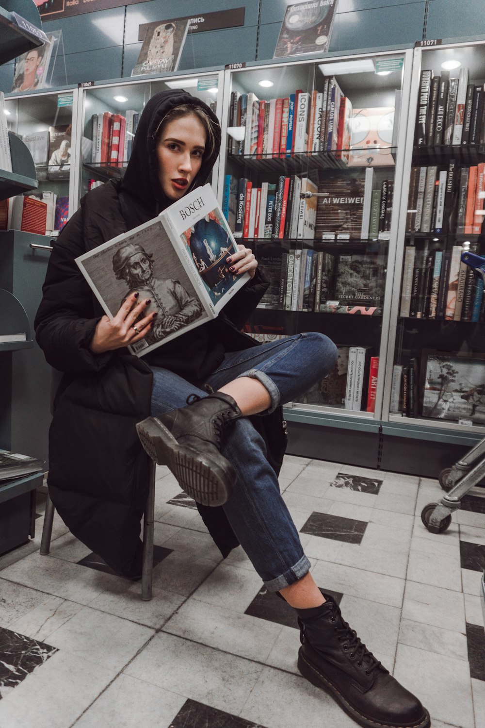 woman sits on chair while holding book at the library