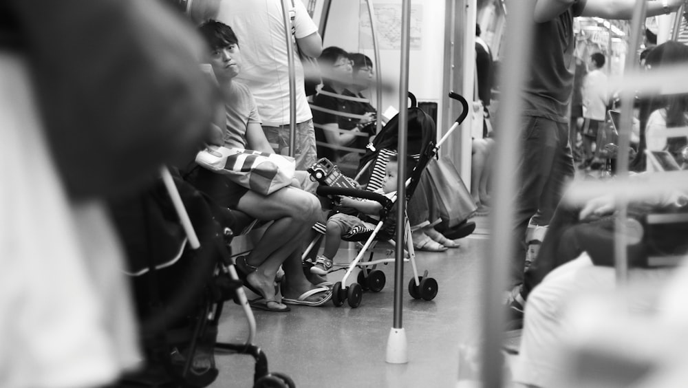grayscale photography of baby on stroller in train