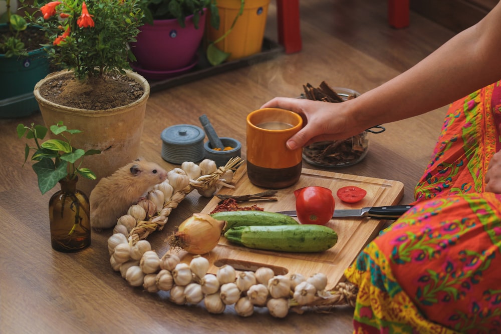 person having coffee while slicing vegetables