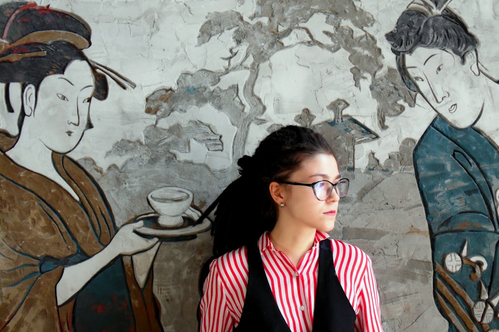 woman taking photo while leaning on wall with Japanese artwork paint