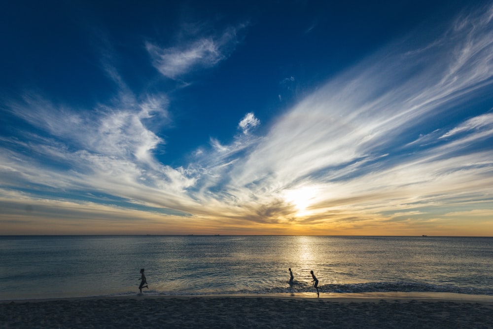 three people running on seashore