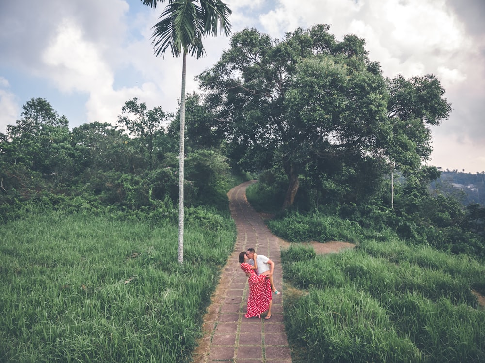 man kissing woman while standing at middle of walkway