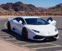 A sleek car parked with a scenic view of the Alps in the background.