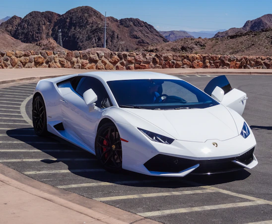 A sleek Lamborghini Huracán STO parked on a winding mountain road with Dolomite peaks in the background at sunset.
