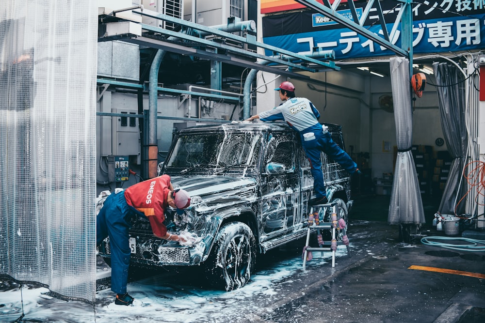 dos hombres lavando SUV negro