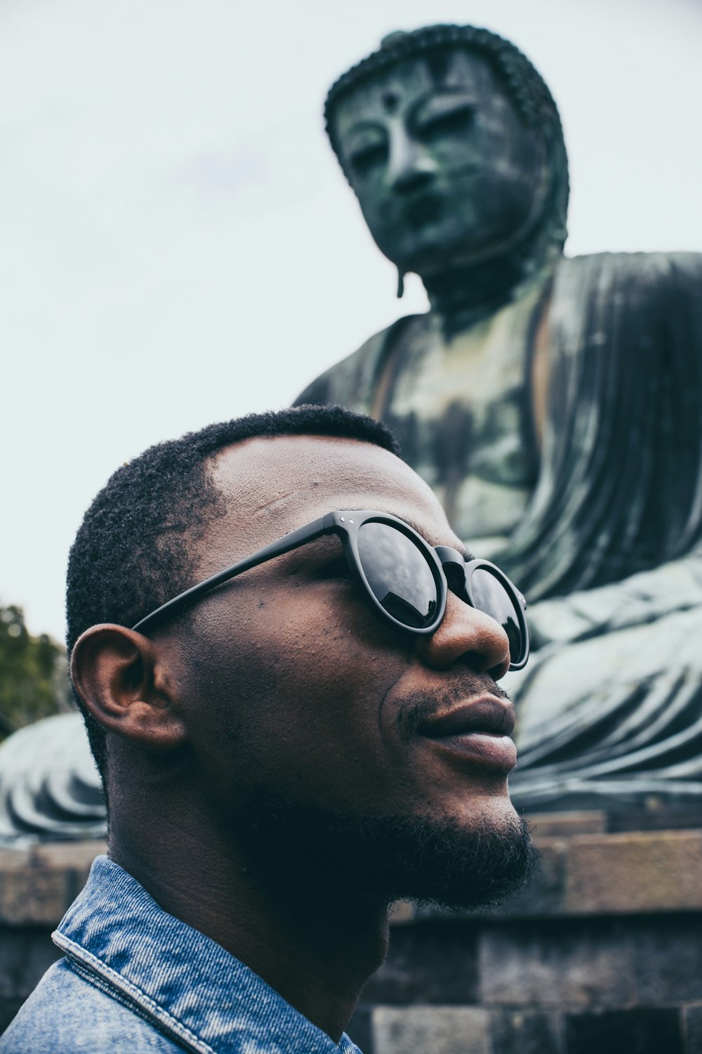 man wearing sunglasses near Buddha statue