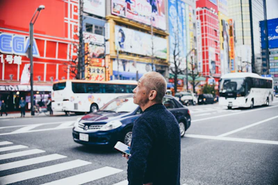 man standing on crosswalk near vehicles