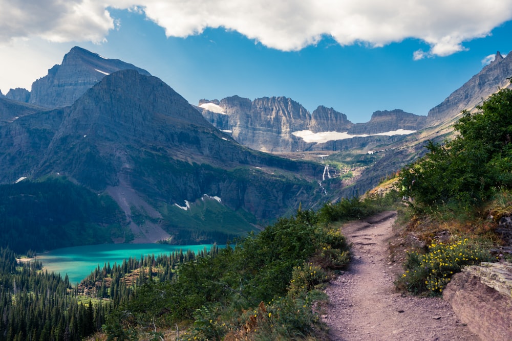 mountains between blue lake under blue and white sky