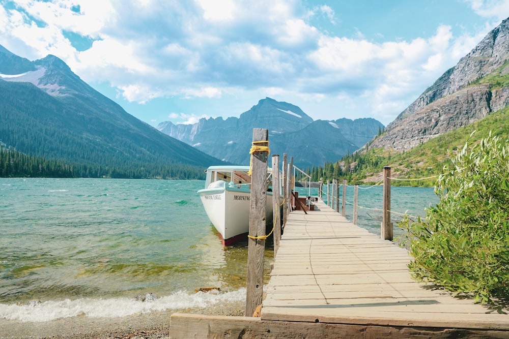 white boat on body of water beside dock during daytime