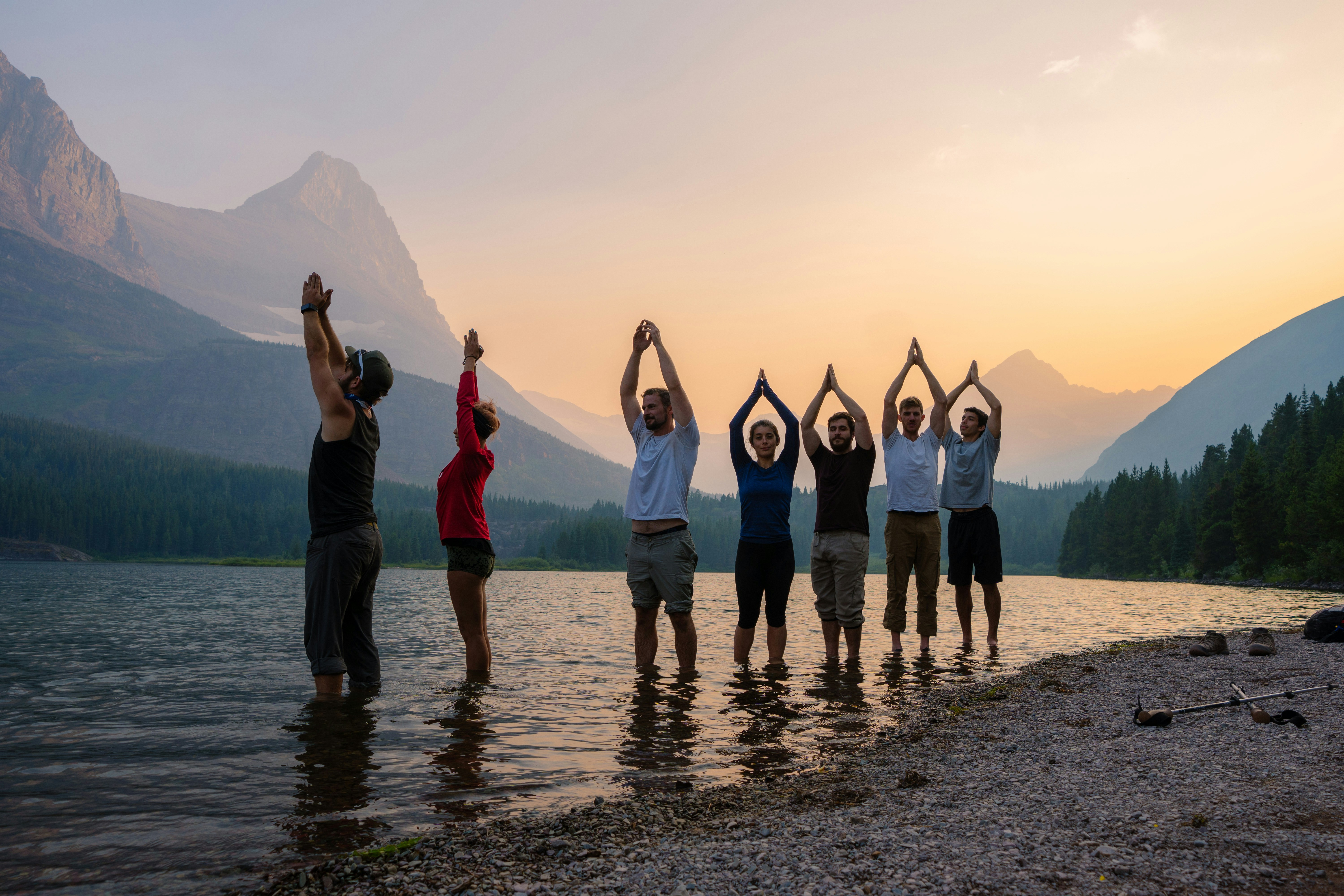 people standing on seashore while raising hands