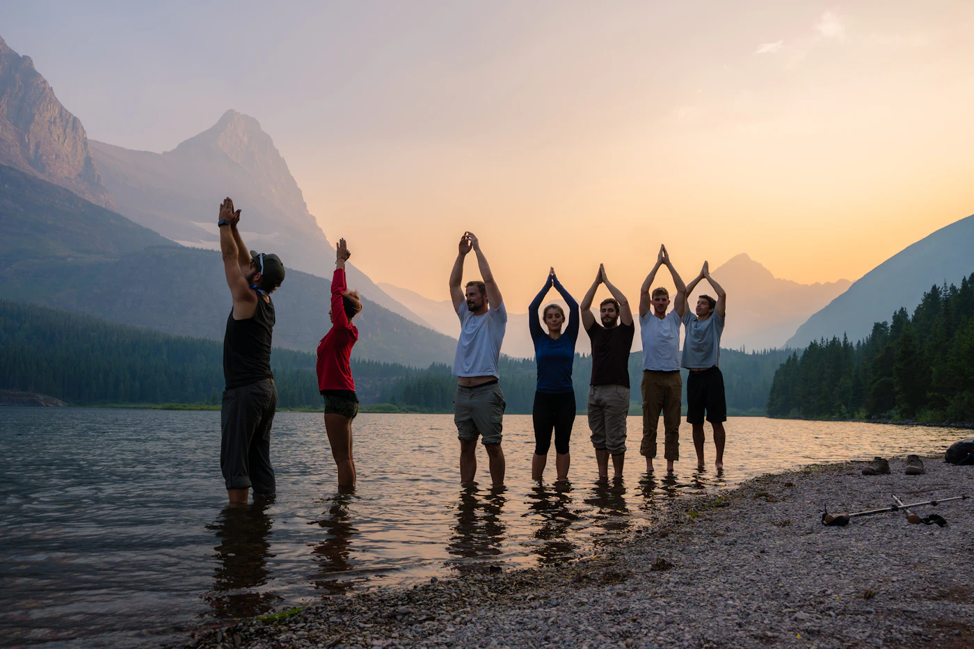 Équipe réunie au bord d'un lac de montagne au coucher du soleil