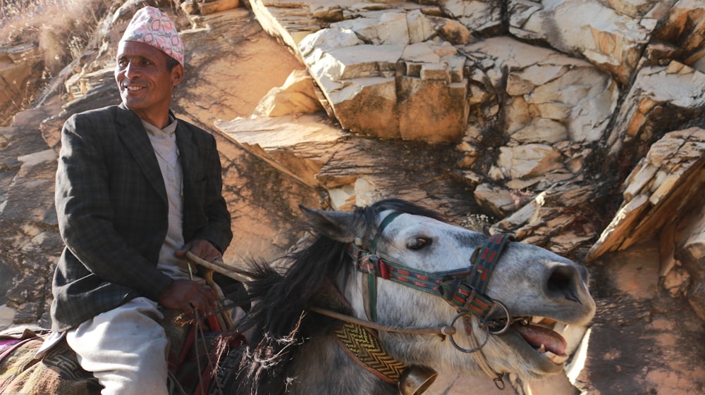 man in gray suit jacket riding horse while smiling