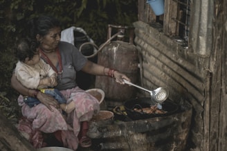 woman cooking while cuddling a child