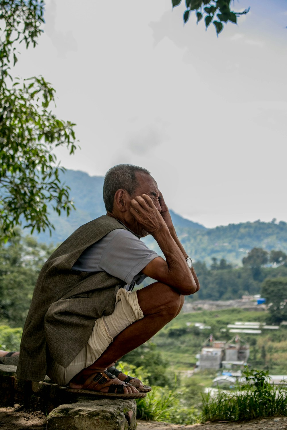 man sitting on rock while holding his face