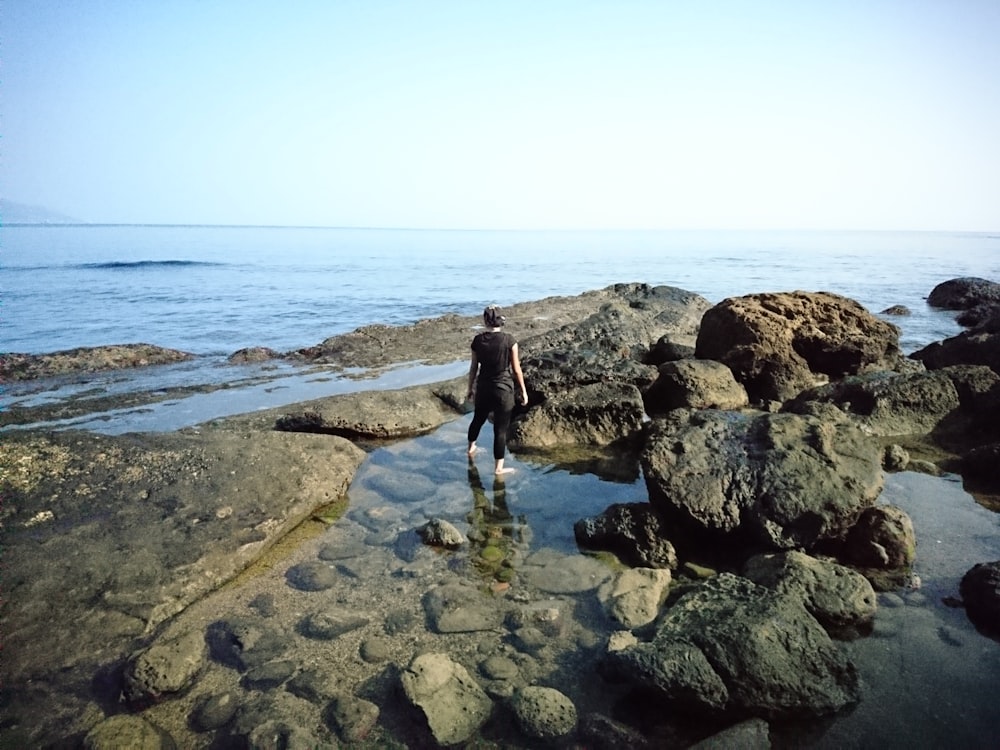 woman in black shirt on rocky beach during daytime