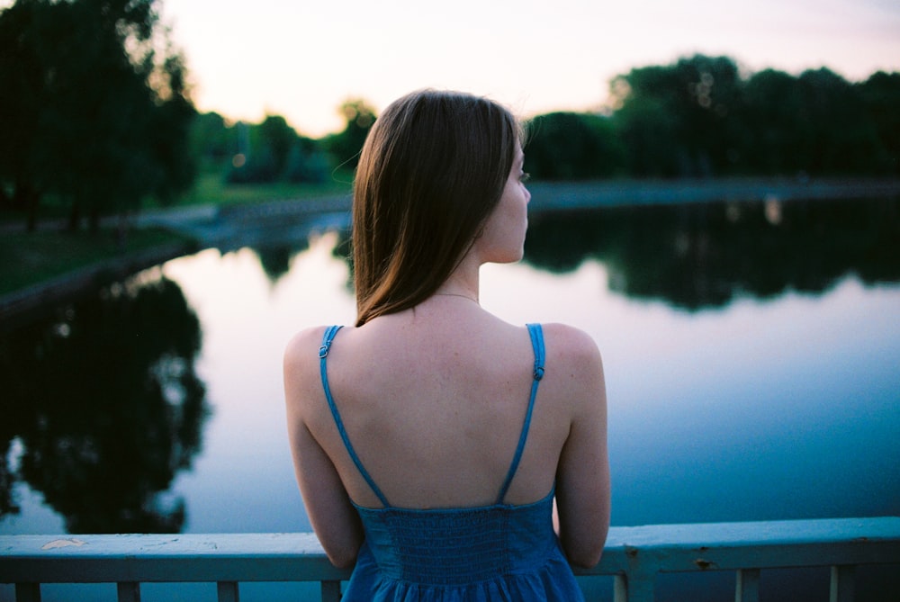 woman leaning on metal fence facing body of water