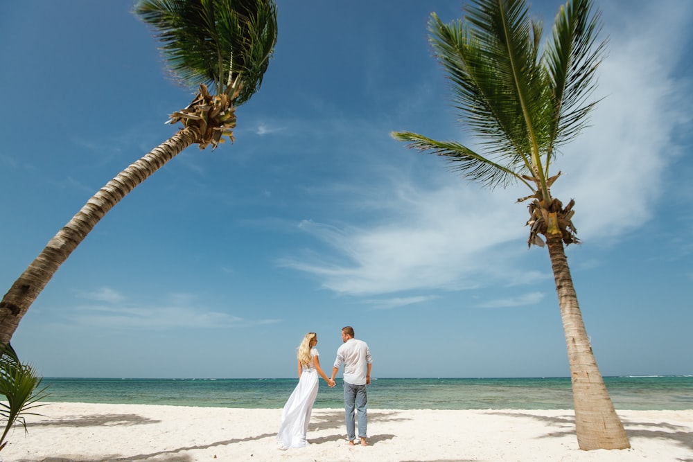 man and woman stands on white sand while holding each other hand