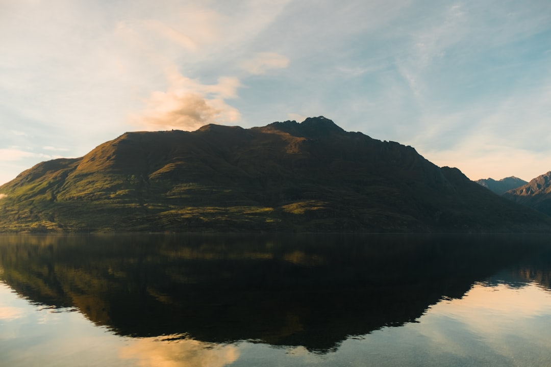 body of water beside mountain under clear blue sky