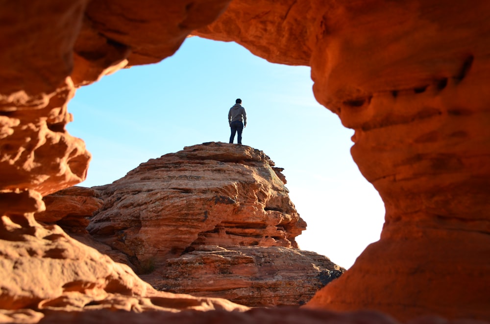 uomo in piedi sulla formazione rocciosa marrone