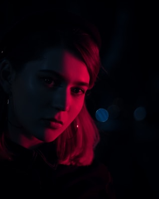 A moody boudoir portrait with soft shadows and warm reddish tones.