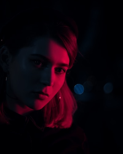 A close-up portrait of an artist in a dimly lit studio, bathed in soft gold light.